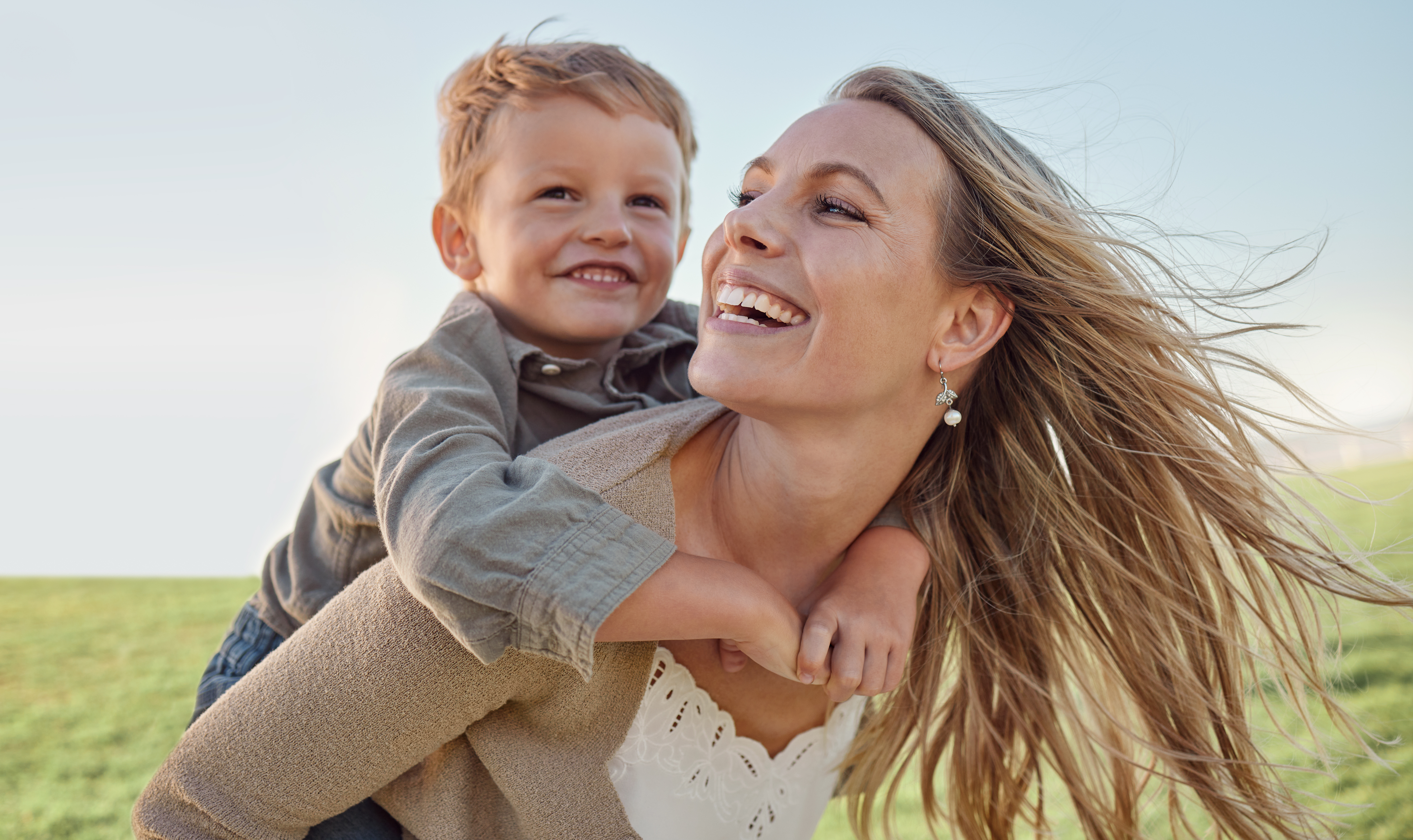 A mother and her son laughing together in an open field